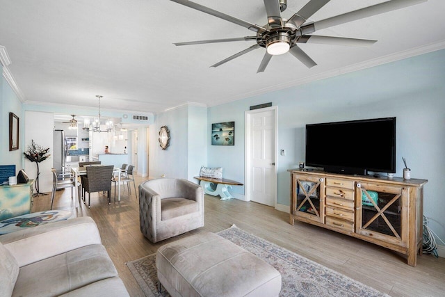 living area with light wood-style floors, ornamental molding, baseboards, and ceiling fan with notable chandelier