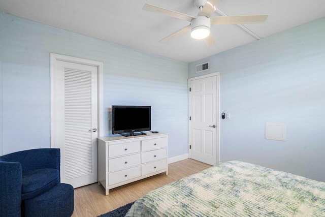 bedroom featuring a ceiling fan, visible vents, light wood-style flooring, and baseboards