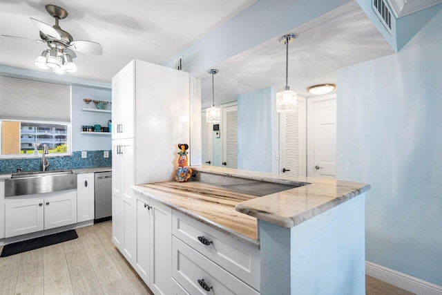 kitchen featuring light wood finished floors, white cabinetry, a sink, light stone countertops, and dishwasher