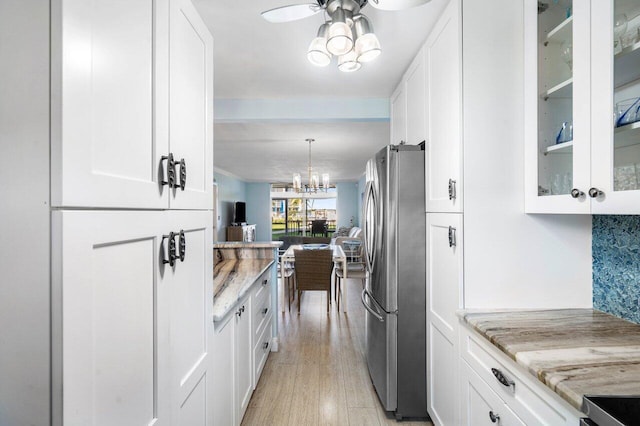 kitchen with white cabinetry, light stone counters, and freestanding refrigerator