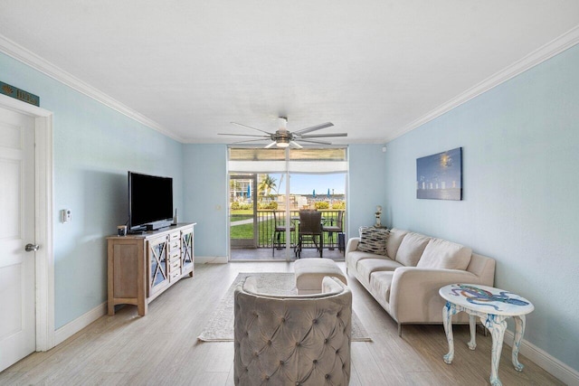 living area with ornamental molding, light wood-style flooring, baseboards, and a ceiling fan