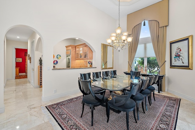 dining area with marble finish floor, a high ceiling, a notable chandelier, and baseboards