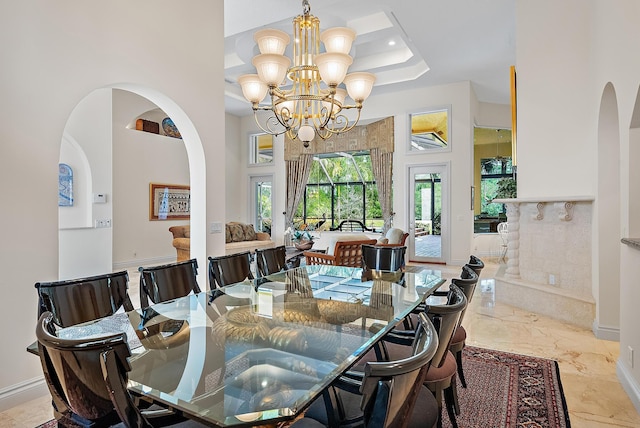 dining area with a towering ceiling, marble finish floor, baseboards, and arched walkways