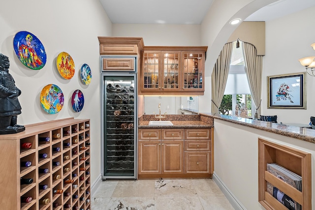 wine room featuring beverage cooler, wet bar, arched walkways, and a sink