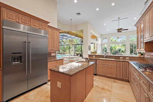 kitchen featuring stainless steel appliances, a sink, visible vents, marble finish floor, and dark stone counters