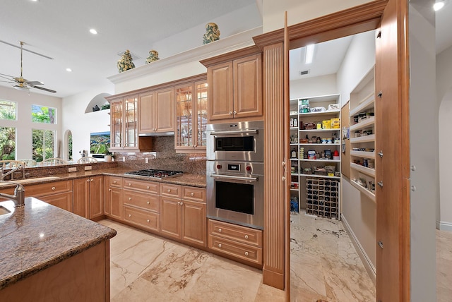 kitchen with marble finish floor, appliances with stainless steel finishes, dark stone counters, and a sink