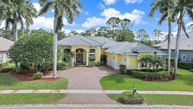 view of front of property featuring a garage, a tile roof, a front lawn, and decorative driveway