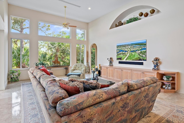 living area featuring arched walkways, recessed lighting, a towering ceiling, a ceiling fan, and baseboards