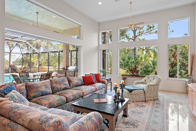 living area with a healthy amount of sunlight, a sunroom, a towering ceiling, and baseboards