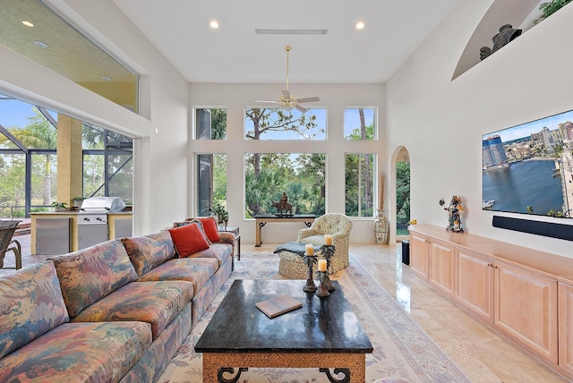 living room with a high ceiling, a wealth of natural light, and recessed lighting