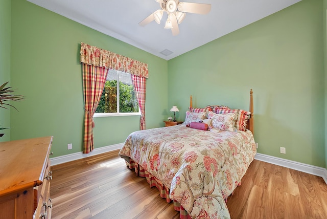 bedroom featuring lofted ceiling, baseboards, and wood finished floors