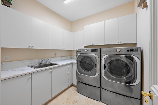 washroom featuring cabinet space, washing machine and dryer, and a sink