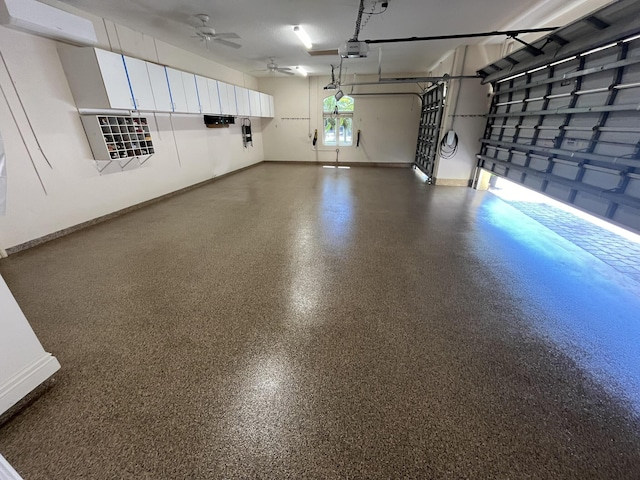 garage with a garage door opener, ceiling fan, and baseboards