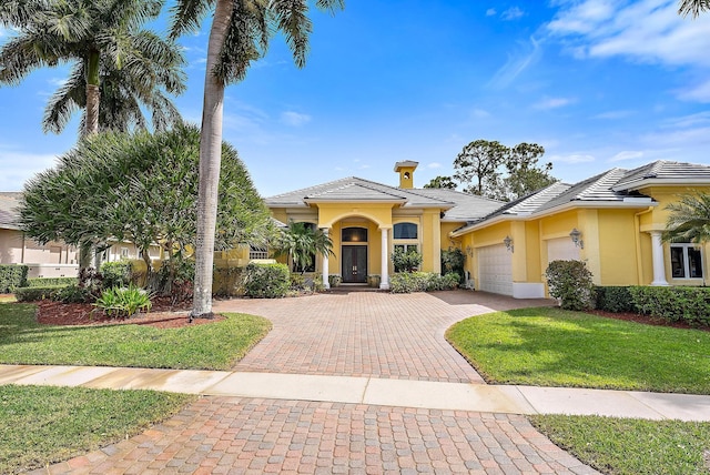 view of front of property with a garage, a tiled roof, decorative driveway, and stucco siding