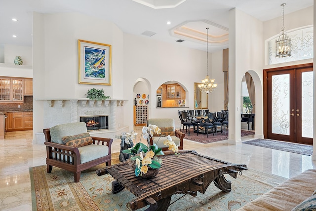 entryway with a high ceiling, a premium fireplace, marble finish floor, french doors, and an inviting chandelier