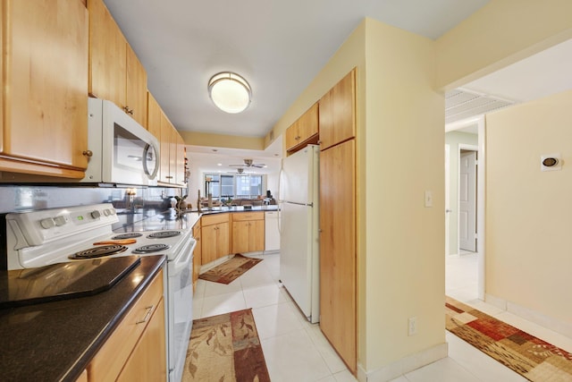 kitchen with light brown cabinetry, light tile patterned flooring, white appliances, a peninsula, and baseboards