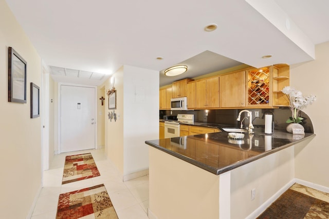 kitchen featuring white appliances, dark countertops, a peninsula, open shelves, and a sink