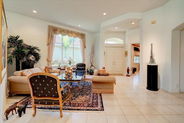 living room with light tile patterned flooring, recessed lighting, arched walkways, and baseboards