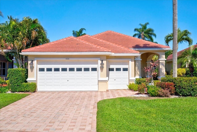 view of front of house featuring stucco siding, a tiled roof, decorative driveway, and a front yard