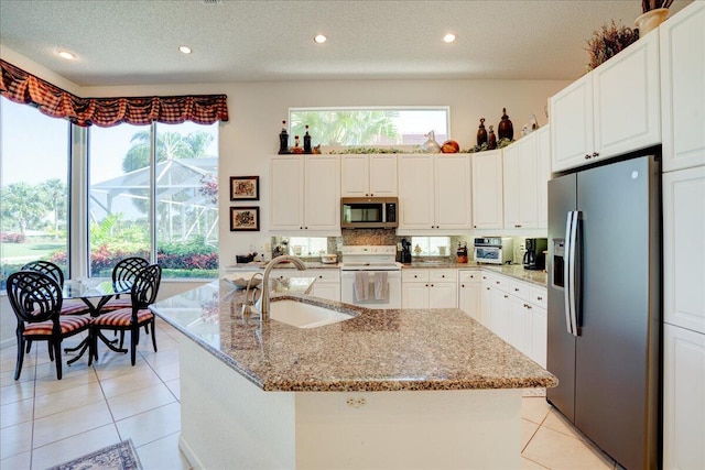 kitchen with a sink, stainless steel appliances, light stone countertops, and light tile patterned flooring