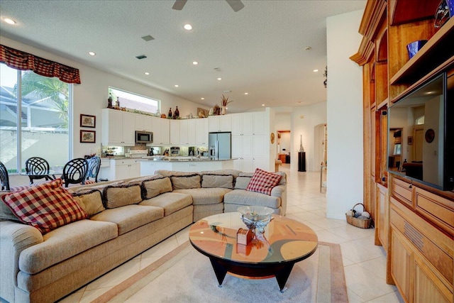 living room with a ceiling fan, light tile patterned floors, recessed lighting, and a textured ceiling