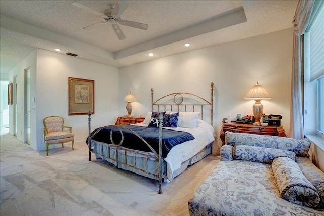 bedroom featuring a tray ceiling, visible vents, and light colored carpet