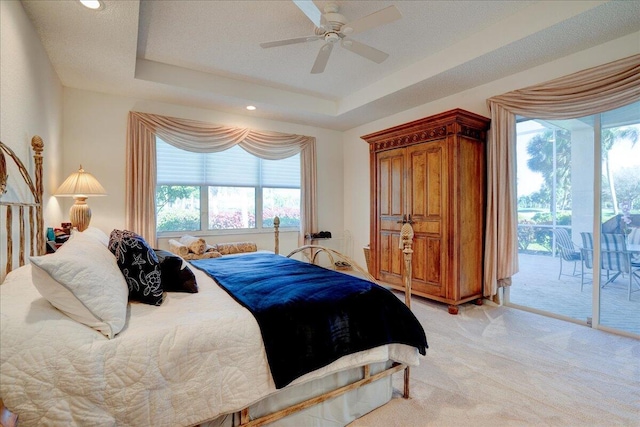 bedroom featuring ceiling fan, access to exterior, a raised ceiling, and light carpet