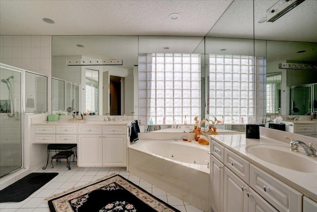 bathroom featuring a sink, a textured ceiling, a tub with jets, a shower stall, and tile patterned flooring