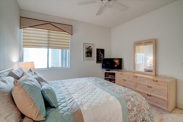 bedroom with a textured ceiling, light colored carpet, and ceiling fan