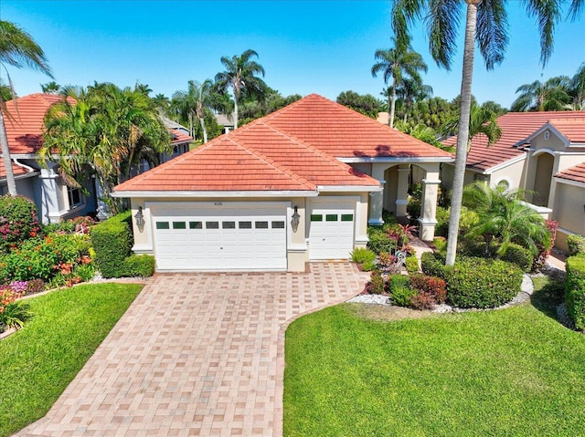 mediterranean / spanish home with stucco siding, decorative driveway, a front yard, an attached garage, and a tiled roof