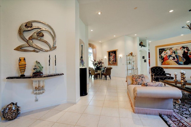 living area featuring light tile patterned flooring, recessed lighting, arched walkways, and baseboards