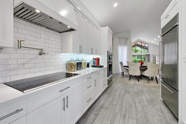 kitchen featuring appliances with stainless steel finishes, white cabinets, and premium range hood