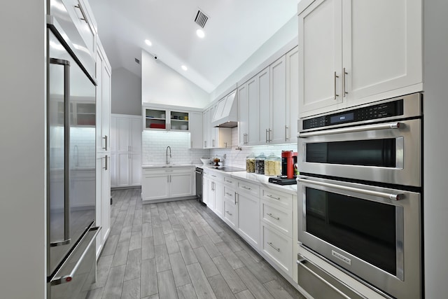 kitchen with visible vents, appliances with stainless steel finishes, vaulted ceiling, light countertops, and backsplash