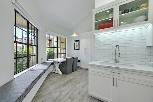 kitchen with tasteful backsplash, a sink, white cabinets, and light wood-style floors