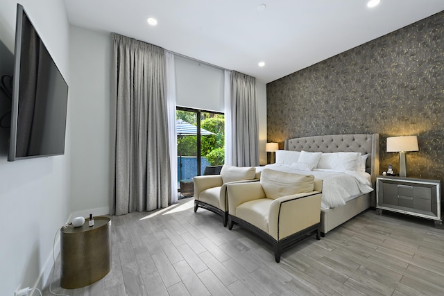 bedroom featuring light wood finished floors, an accent wall, wallpapered walls, and recessed lighting