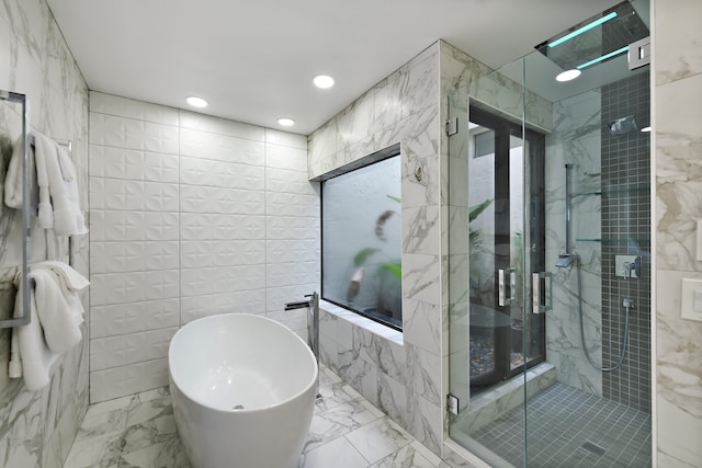 bathroom featuring marble finish floor, tile walls, a freestanding bath, and a stall shower