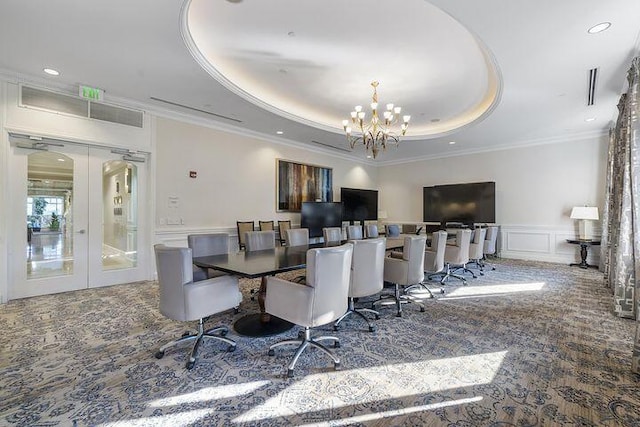 carpeted dining space with a notable chandelier, french doors, a raised ceiling, and a decorative wall