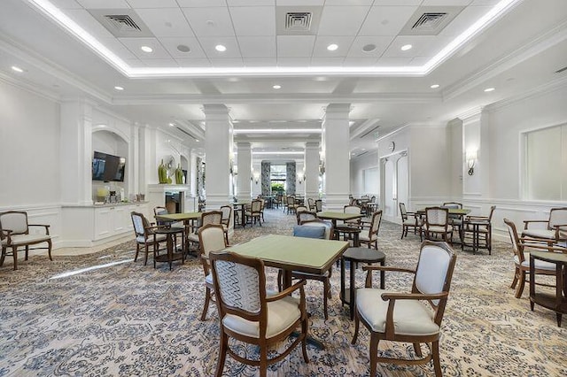 dining space with a tray ceiling, visible vents, a decorative wall, and decorative columns