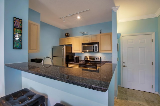 kitchen featuring baseboards, dark stone counters, appliances with stainless steel finishes, a peninsula, and light brown cabinets