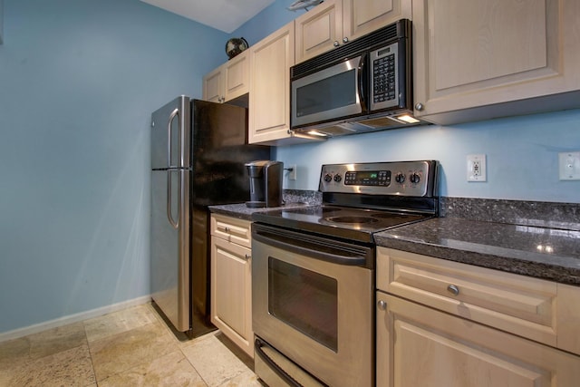 kitchen featuring stainless steel appliances, dark stone countertops, and baseboards