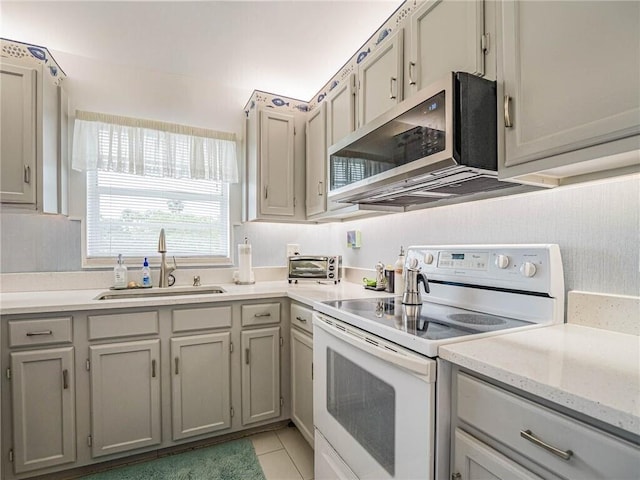 kitchen with white electric stove, stainless steel microwave, gray cabinetry, a sink, and light tile patterned flooring