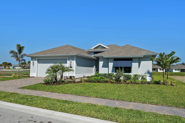 view of front of home featuring an attached garage, a shingled roof, decorative driveway, and a front yard