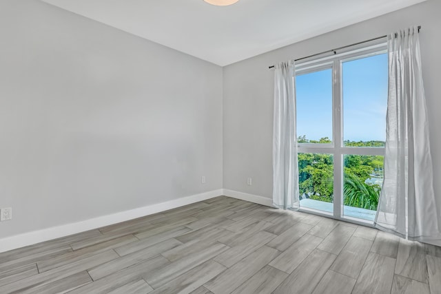 spare room with baseboards and wood finish floors