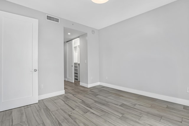 empty room featuring visible vents, baseboards, and wood finished floors