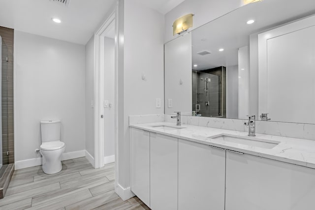 full bath featuring toilet, a stall shower, baseboards, and a sink