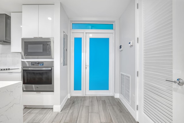 interior space featuring visible vents, white cabinetry, stainless steel oven, light stone countertops, and built in microwave