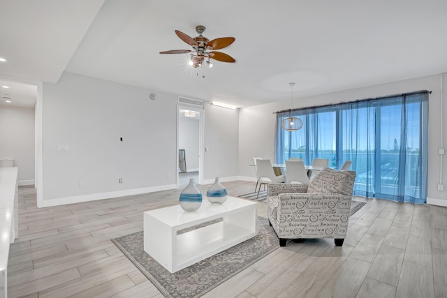 living room with ceiling fan, visible vents, baseboards, and wood finish floors