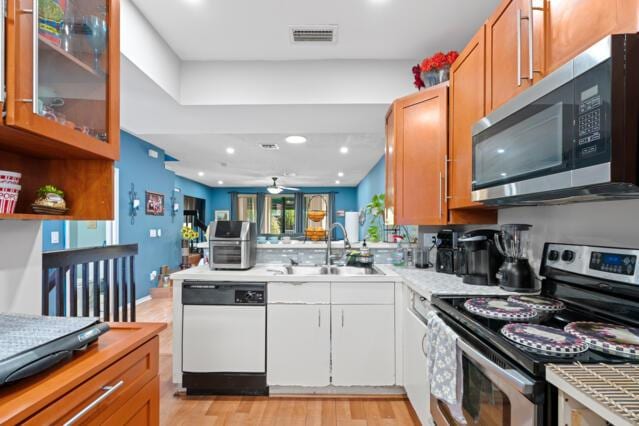 kitchen with visible vents, a peninsula, stainless steel appliances, light countertops, and a sink