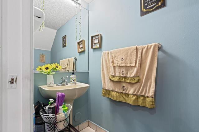 bathroom featuring a textured ceiling, vaulted ceiling, and a sink