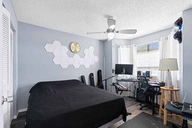 bedroom featuring ceiling fan, a textured ceiling, baseboards, and wood finished floors